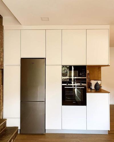 a kitchen with white cabinets and a refrigerator at Quinta da Azenha in Nespereira