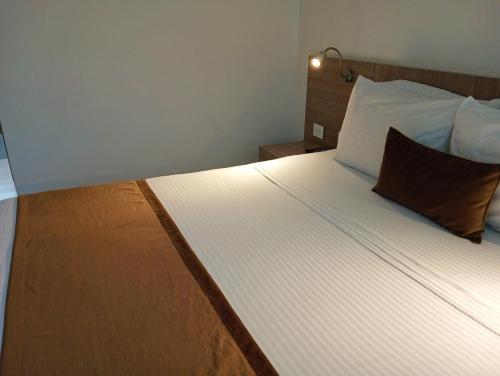 a bedroom with a large white bed with two pillows at Hotel Lomas 10 Medellin in Medellín