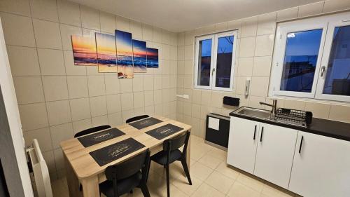 une cuisine avec une table, des chaises et un évier dans l'établissement Grey And White Duplex, à Drancy