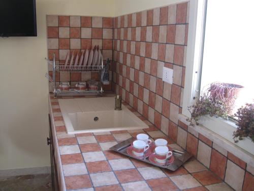 a tiled bathroom with a tub with cups on a tray at VALDERICE VACANZE biker's friend in Valderice