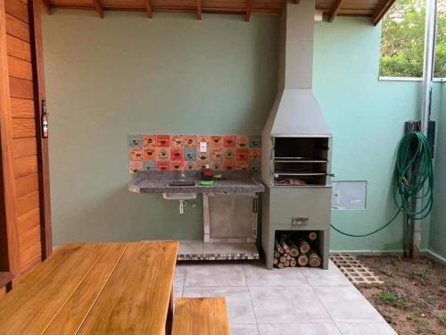 an outdoor kitchen with a stove and a wooden table at Chalé em meio a natureza de bonitoms in Bonito