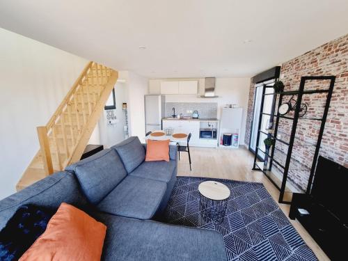 - un salon avec un canapé bleu et un mur en briques dans l'établissement Dépendance cosy en duplex avec terrasse & jardin, à Valleiry