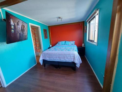 Schlafzimmer mit einem Bett mit einer roten und blauen Wand in der Unterkunft Cómoda casa familiar in Valdivia