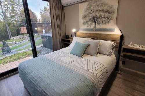 una camera da letto con un letto e una grande finestra di Emeraude des Sources Lac spa sauna et hammam a Brownsburg