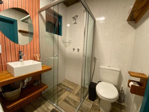 a bathroom with a shower and a toilet and a sink at Morada na Serra chalé com hidromassagem, deck, churrasqueira in Gonçalves