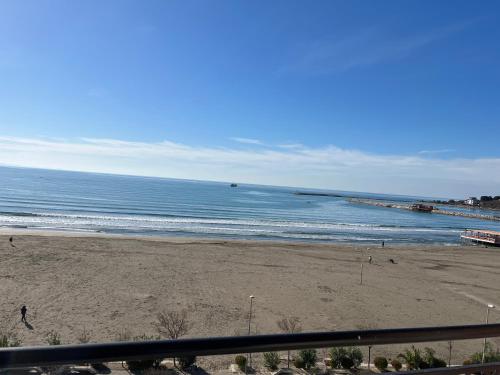 a beach with people walking on the sand and the ocean at Hotel Brilant in Shëngjin