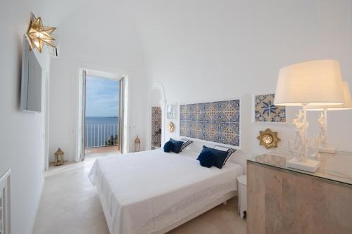 a white bedroom with a bed and a large window at Estate4home - Regina Dar adults only in Positano