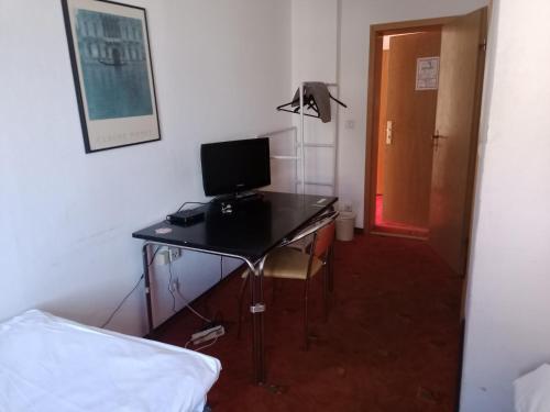 a desk with a computer on it in a bedroom at Hotel Pension zur Tanne in Zwickau