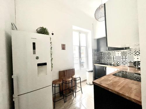 La cuisine est équipée d'un réfrigérateur blanc et de tabourets de bar. dans l'établissement Cosy Family trip, à Nice