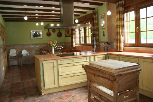 a large kitchen with green walls and wooden cabinets at Casa las Vacas in Cervera de Pisuerga