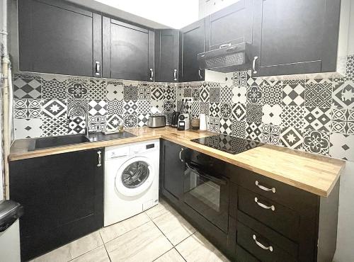 - une cuisine avec des armoires noires et un lave-linge dans l'établissement Cosy Family trip, à Nice