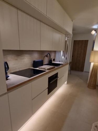 une cuisine avec des armoires blanches et un four à plaques de cuisson dans l'établissement Appartement Manieldi - Golfe de St-Tropez, à Gassin