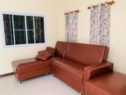 a brown leather couch in a room with two windows at นิลแลนด์ รีสอร์ท in Ban Tha Dan