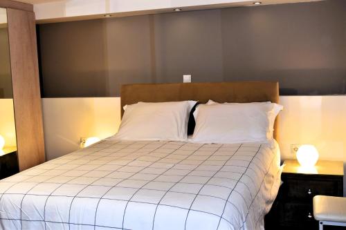 a bedroom with a bed with white sheets and two lamps at Panorama Γλυκά Νερά - Athens in Glyka Nera
