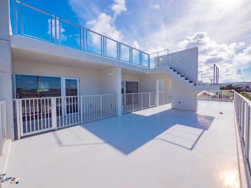 a house with a balcony with a staircase at Resort House Ricca in Nanjo