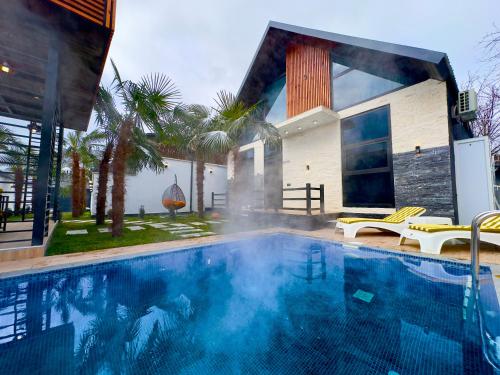 a large swimming pool in front of a house at Qafqaz Retro Bungalow HOT POOL in Gabala