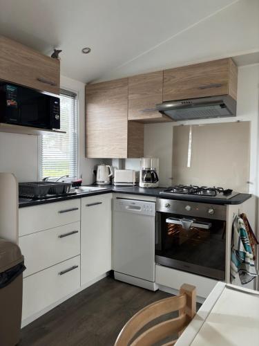 une cuisine avec des armoires blanches et un four à plaques de cuisson dans l'établissement Mh 3 ch - 1 sdb - terrasse couverte - kerlann, à Pont-Aven