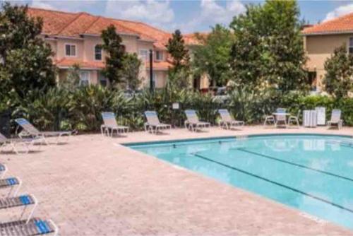 a large swimming pool with chairs and a building at Home Near Disney Private Pool & Playground in Howey in the Hills