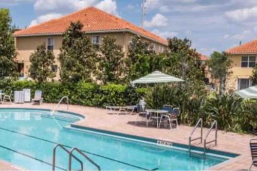 a swimming pool with chairs and tables and umbrellas at Home Near Disney Private Pool & Playground in Howey in the Hills