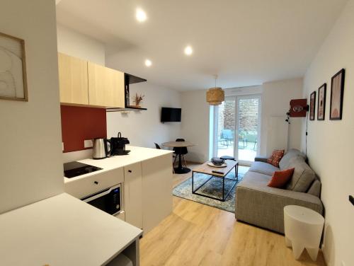une cuisine et un salon avec un canapé et une table dans l'établissement Beau et calme T1 avec Terrasse au coeur de Kerinou, à Brest