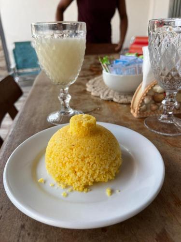 une assiette blanche avec un dessert jaune sur une table dans l'établissement Suítes Cantinho do Ze em Milagres, à São Miguel dos Milagres