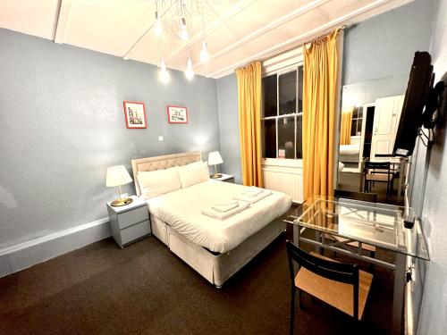 a bedroom with a bed and a glass table at Kensington Gardens in London