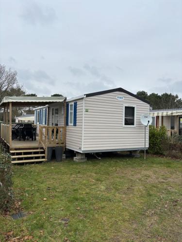 Une grande caravane blanche avec terrasse couverte dans la cour dans l'établissement Mh 3 ch - 1 sdb - terrasse couverte - kerlann, à Pont-Aven