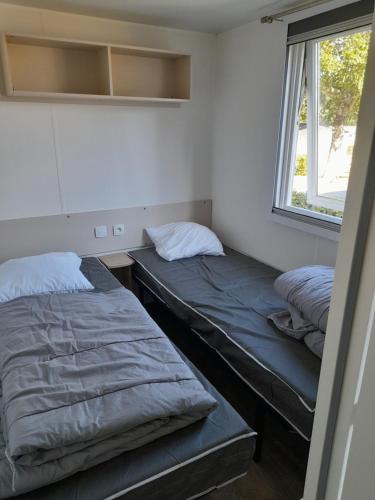 deux lits assis dans une pièce avec une fenêtre dans l'établissement Mh 3 ch - 1 sdb - terrasse couverte - kerlann, à Pont-Aven