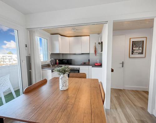a kitchen and dining room with a wooden table at Chic & lumineux avec balcon in Calais