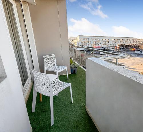 two chairs sitting on a balcony with green grass at Chic & lumineux avec balcon in Calais