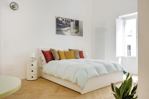 een witte slaapkamer met een wit bed en kleurrijke kussens bij Coppola Suite in Lecce