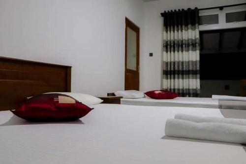 a bedroom with two beds with white sheets and a red pillow at Blue Moon Villa in Waskaduwa