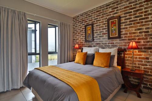 une chambre avec un grand lit avec un mur de briques dans l'établissement Luxury Lowveld Apartment, à Nelspruit