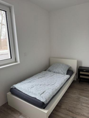 a bed in a white room with a window at Neu und Günstig! Hochwertige Ferien- und Monteurswohnung bei Leipzig Nähe A14 in Taucha