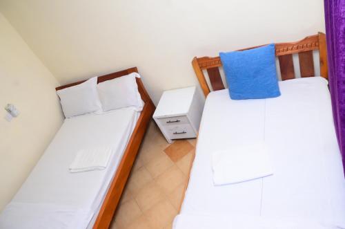 two beds in a small room with a blue pillow at Lifestyle 3 Shanzu 2 bedroom furnished Apartment in Mombasa