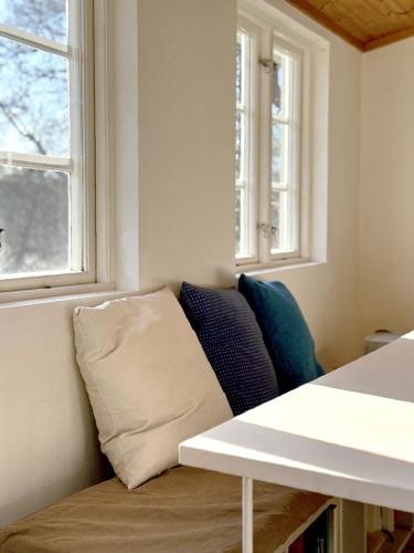 a couch sitting in a room with two windows at Atelier Blå houses in Rösselvik