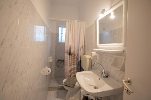 a white bathroom with a sink and a toilet at Μπλε Rooms & Apartments in Chiliadou
