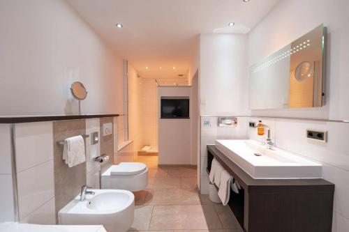a bathroom with two sinks and a toilet and a television at Boutique-Hotel Bayerischer Hof in Kempten