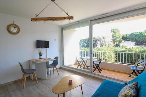 un salon avec un canapé bleu et une grande fenêtre dans l'établissement Appartement PORT SAINT CYPRIEN, à Saint Cyprien Plage