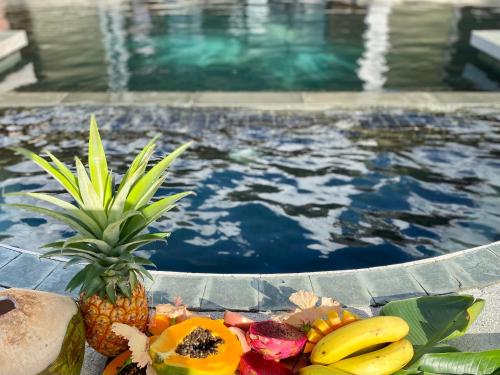 a bowl of fruit next to a swimming pool at Manna Villa - Sovereign Palms CI in Arorangi