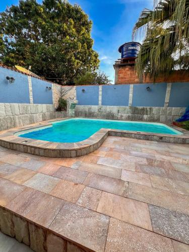 a swimming pool in a yard with a brick wall at kasada Nanda in Pirenópolis