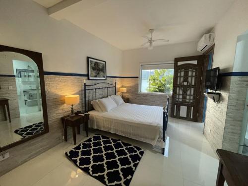 una camera da letto con un letto, uno specchio e una finestra di Studio à Beira Mar em Ilhabela com Vista Deslumbrante IB0001 a Ilhabela