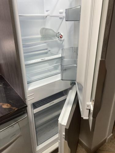 un réfrigérateur vide avec sa porte ouverte dans une cuisine dans l'établissement LA MAISON DU PUITS DE FER à la Flotte en Ré, à La Flotte