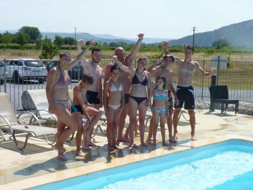 a group of people standing next to a swimming pool at Rev'ôthijol Vacances in Saint Alban Auriolles