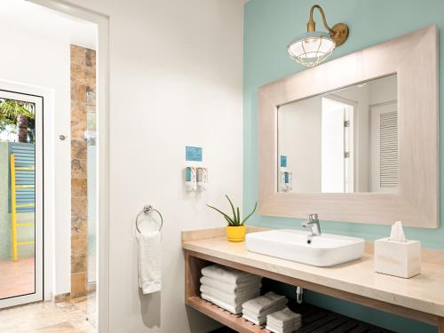 a bathroom with a sink and a mirror at Boardwalk Boutique Hotel Aruba - Adults Only in Palm-Eagle Beach