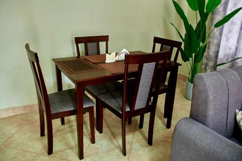 a wooden table with four chairs and a couch at Mvule Homes in Arusha