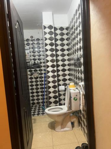 a bathroom with a toilet and black and white tiles at Appartement a settat in Settat