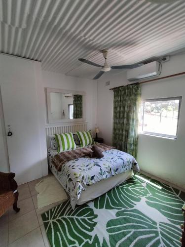 a bedroom with a bed and a green rug at Ocean Rush Dolphin in Zinkwazi Beach