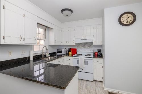 a kitchen with white cabinets and a clock on the wall at New! Special Rate for First Bookings! 2 Bedroom in Charlotte