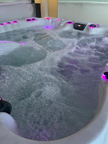 eine mit Wasser gefüllte Badewanne mit rosa Lichtern in der Unterkunft Les oiseaux du paradis in Saint-Antoine-de-Breuilh